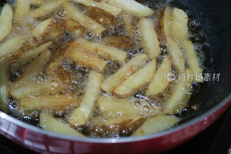 大块的薯片/炸薯条在炸油锅里炸，不健康的饮食